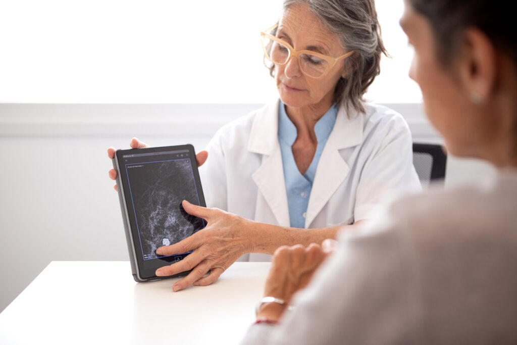 Female gynecologist in consultation with a female patient, analyzing preventive medical exams such as mammograms and transvaginal ultrasounds on her computer and digital tablet - Buenos Aires - Argentina