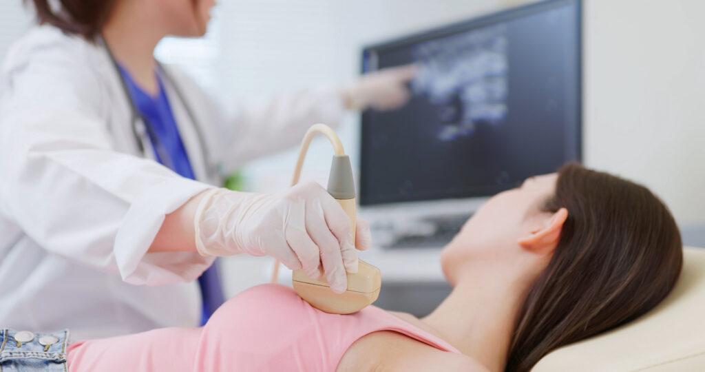 doctor using ultrasound scanner performing examination of breast for her patient - cancer awareness feminine health medical concept