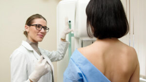 A woman undergoes a mammogram in a modern clinic under the supervision of a doctor. A doctor installs a digital mammograph for a patient. Women's health concept.