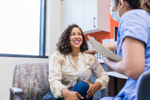 The adult female patient smiles while listening to the doctor give praises about her test results.