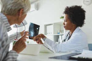 A female doctor sits at her office and examining elderly female patient