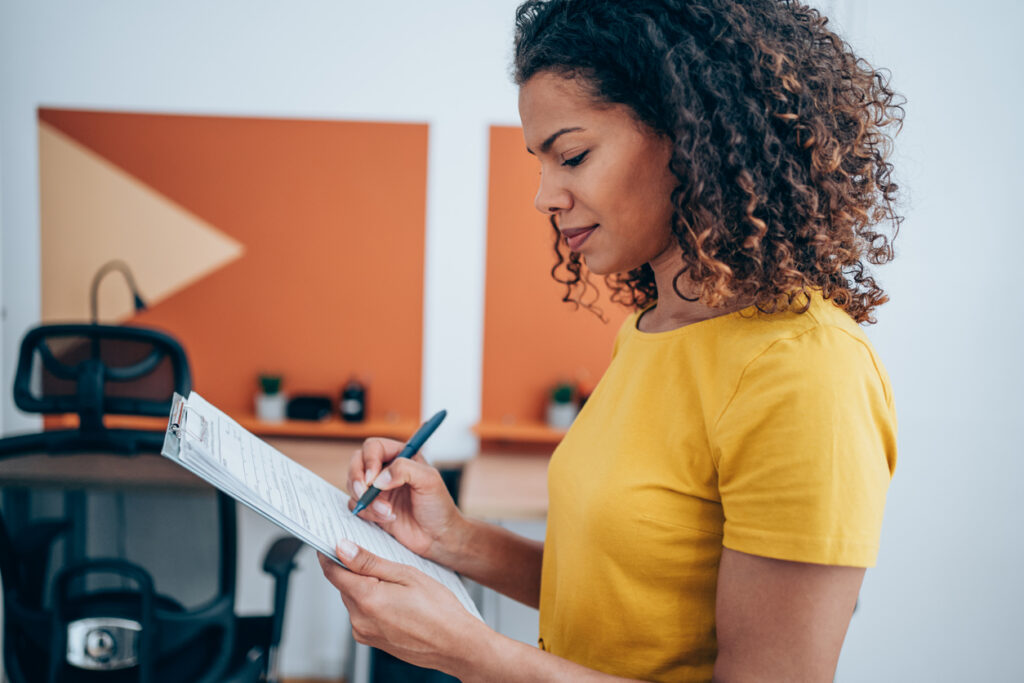 Shot of a businesswoman making notes on a clipboard inside of the office.